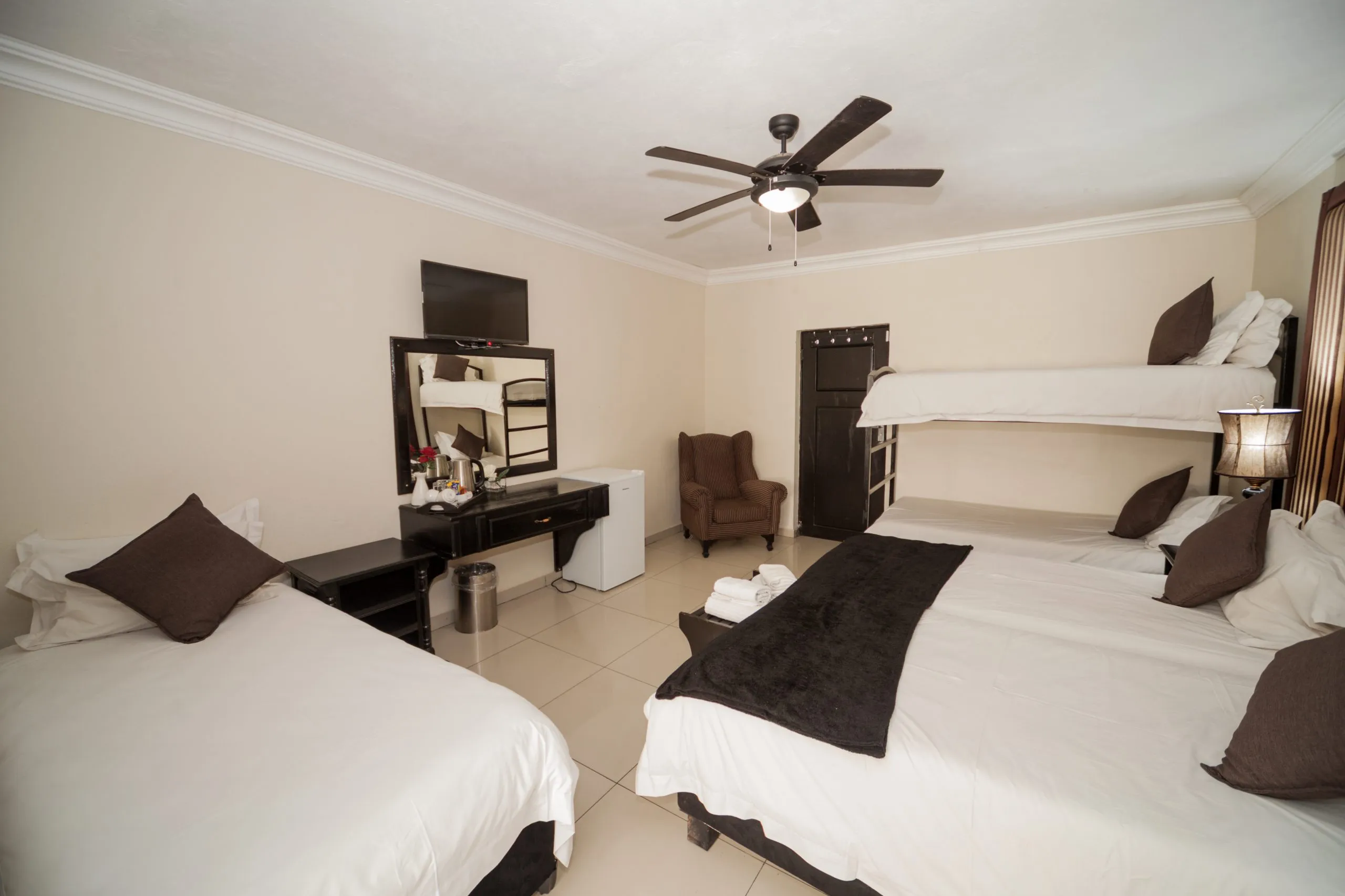 Hotel room with two beds a bunk bed desk and ceiling fan