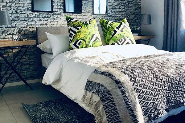 Modern bedroom with patterned pillows textured blanket and stone wall backdrop