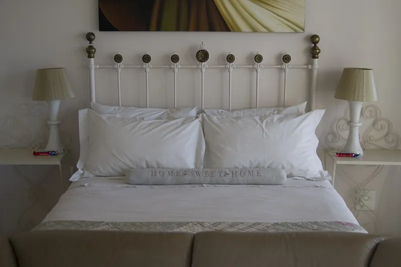 White bed with decorative pillows and lamps on either side in a bedroom
