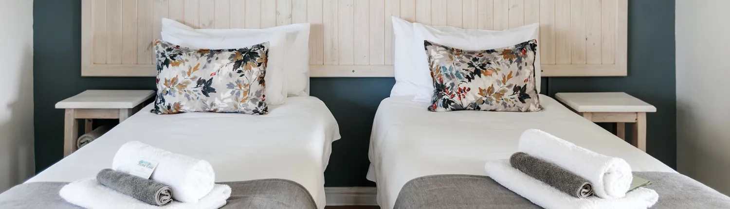 Two neatly made single beds with decorative pillows in a modern bedroom