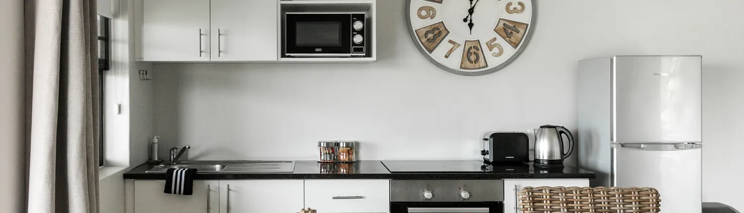 Modern kitchen with black countertops white cabinets and a wall clock
