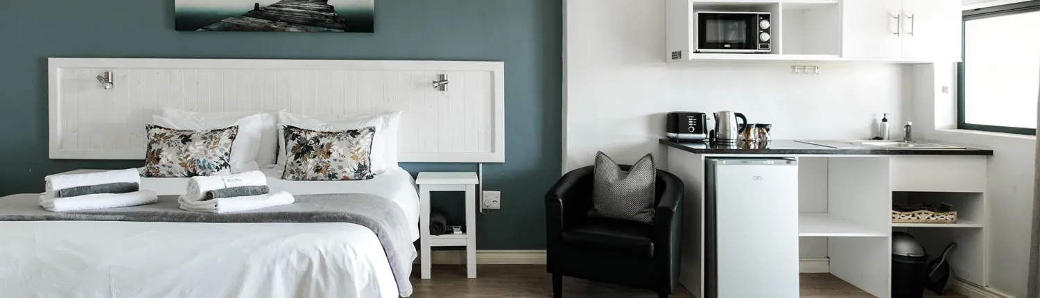 Modern hotel room with a bed armchair kitchenette and large window