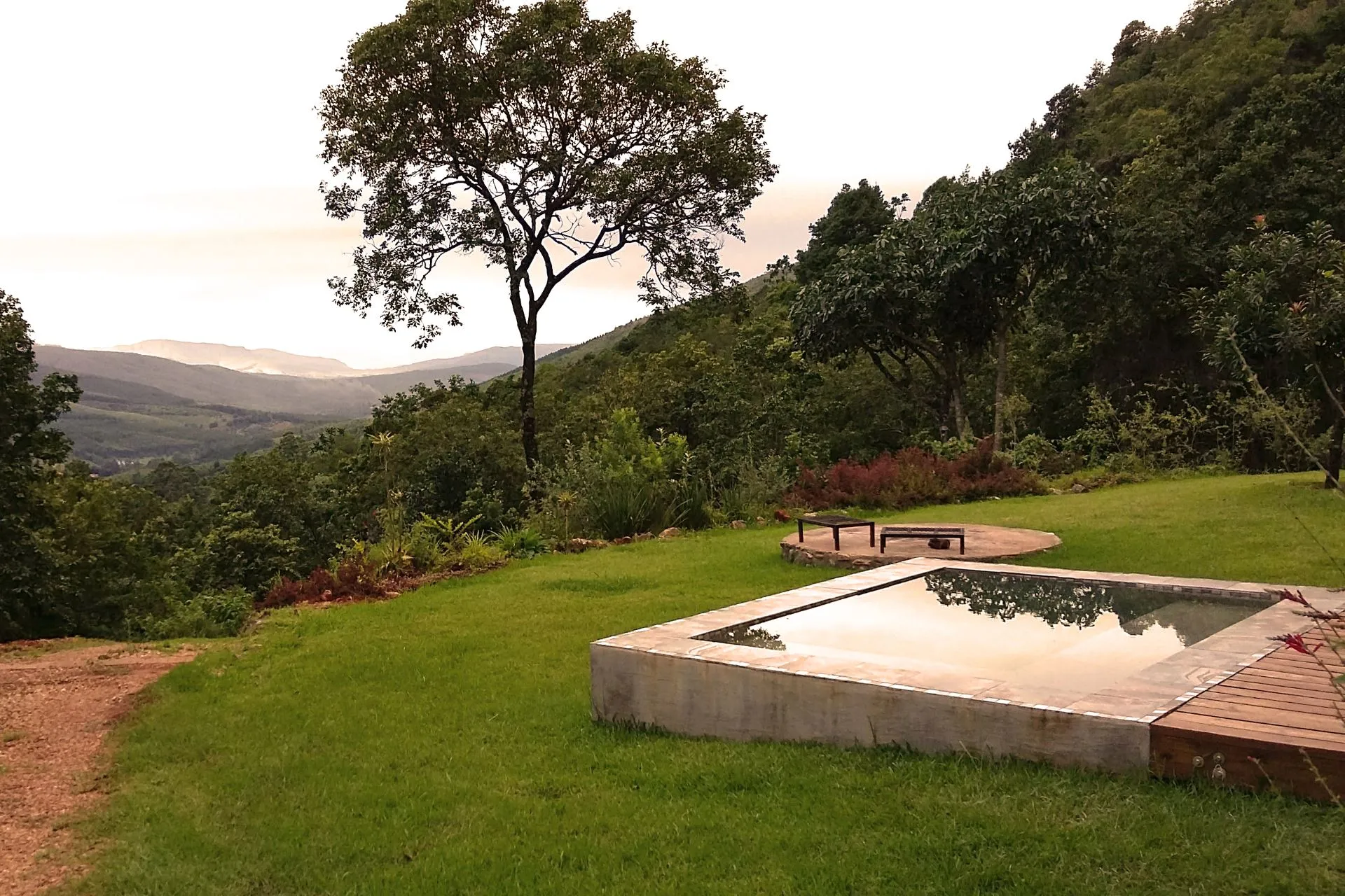 A serene garden with a small pool trees and distant mountains