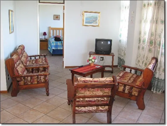 Living room with patterned chairs coffee table TV and view into bedroom