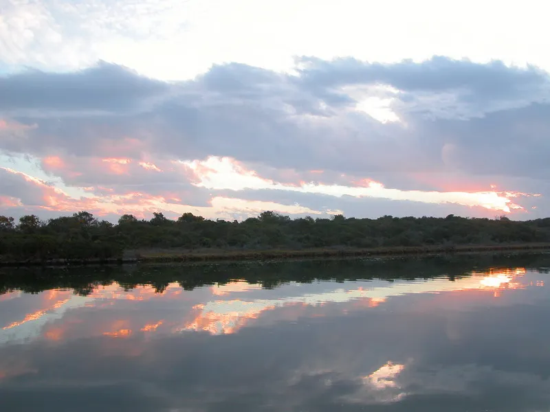 Sunset reflecting on a calm lake with trees in the background