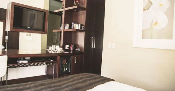 Modern hotel room with bed desk TV and wall art