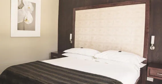 Modern bedroom with a large bed white pillows and dark wooden furniture