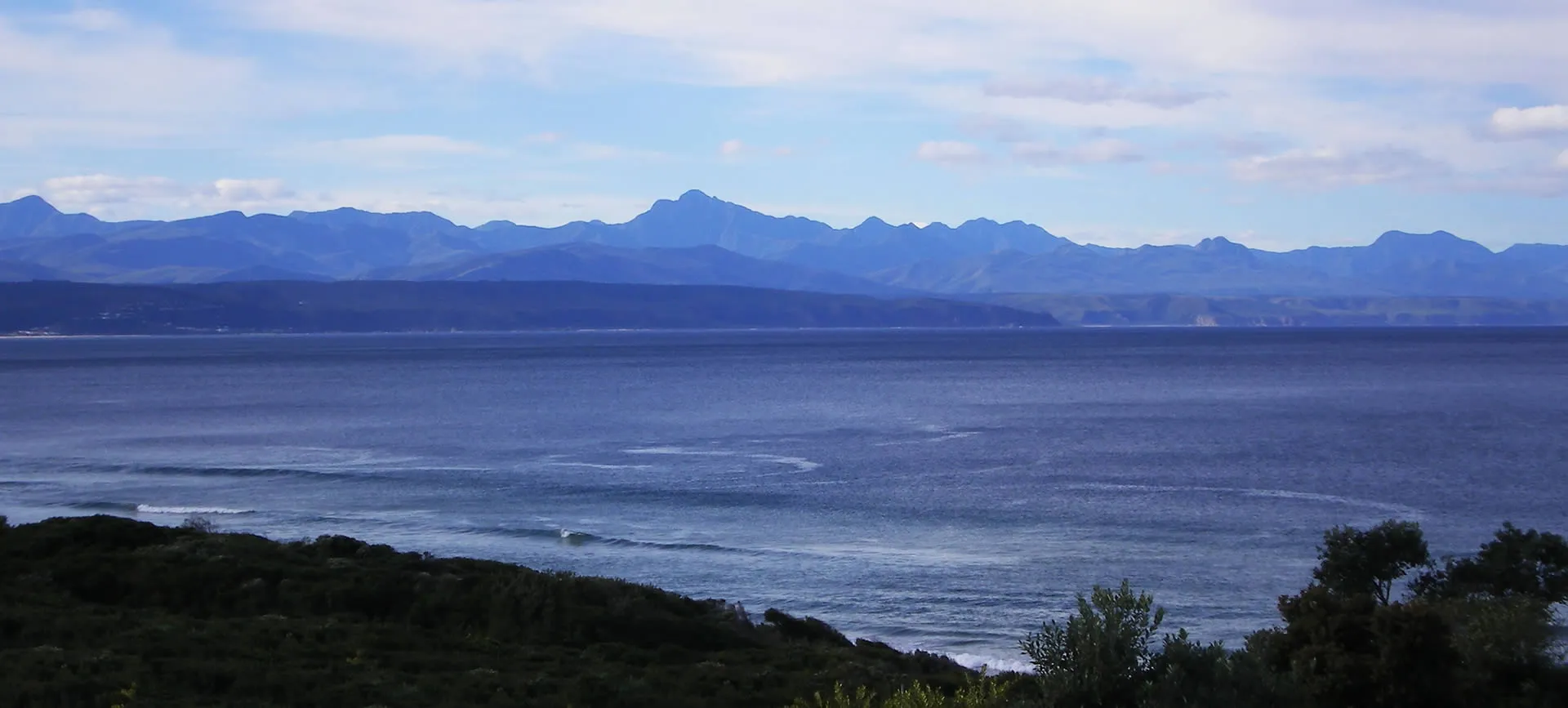 Ocean view with distant mountains and green foreground