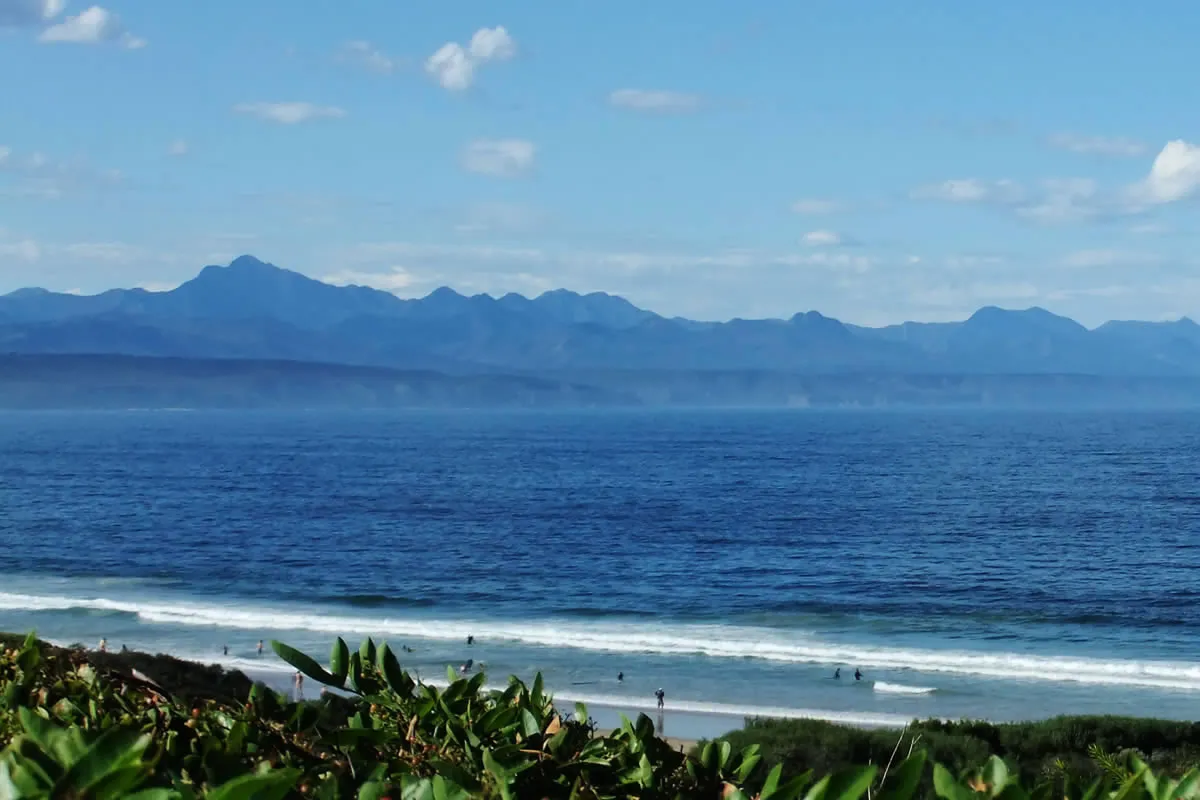 Ocean view with mountains in the background and greenery in the foreground