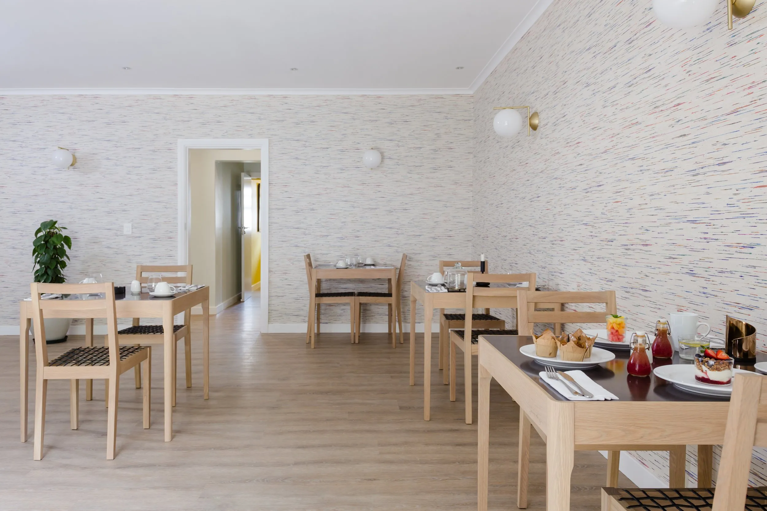 Dining area with wooden tables chairs and breakfast items on a wooden floor