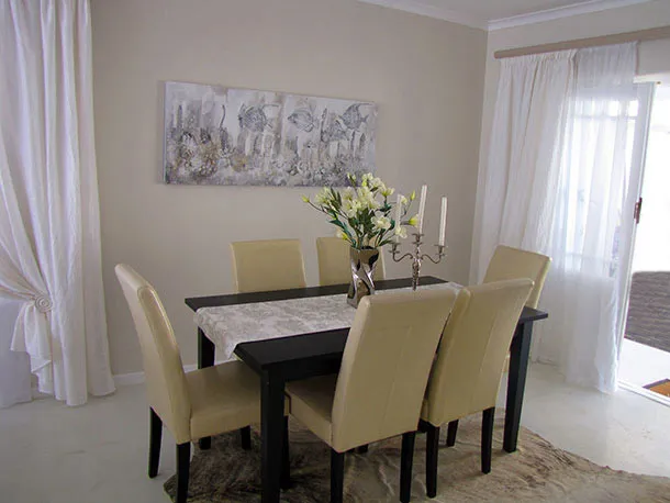 Dining table with six beige chairs floral centerpiece and wall art in a room