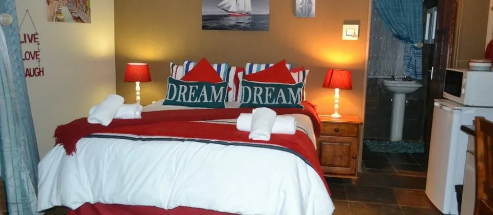 Cozy bedroom with a decorated bed two bedside lamps and a small sink