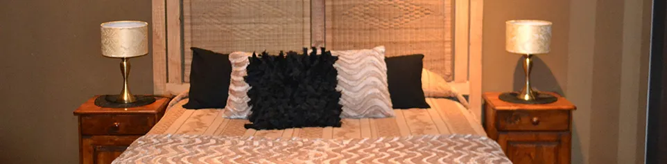 A neatly made bed with pillows flanked by two bedside tables with lamps
