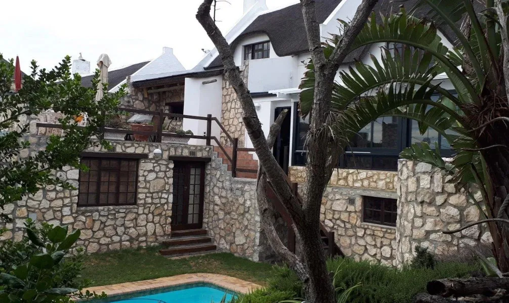 Stone house with pool trees and outdoor stairs in a garden setting