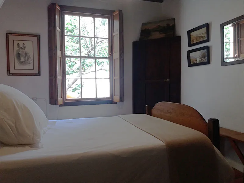 Bedroom with bed window wooden wardrobe framed pictures and mirror