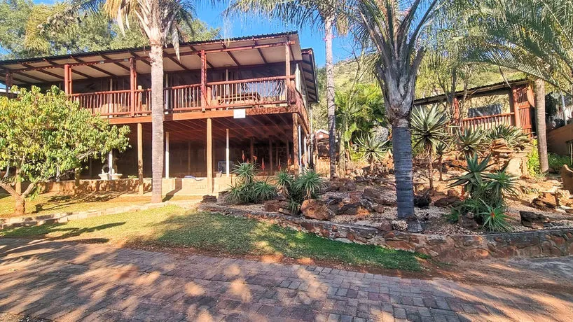 Twostory wooden house with balcony surrounded by palm trees and lush greenery