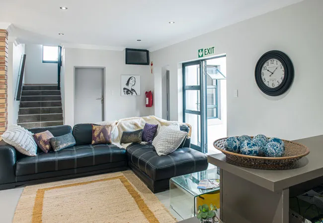 Modern living room with black leather sofa wall clock and exit sign