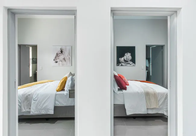 Two doorways showing identical bedrooms with different colored pillows and wall art
