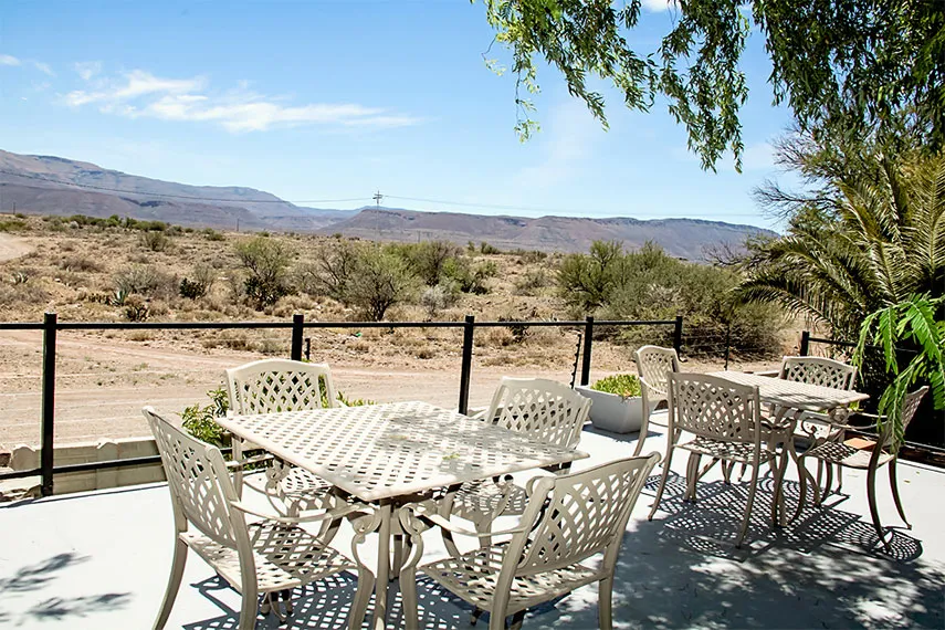 Outdoor patio with white metal furniture overlooking a desert landscape