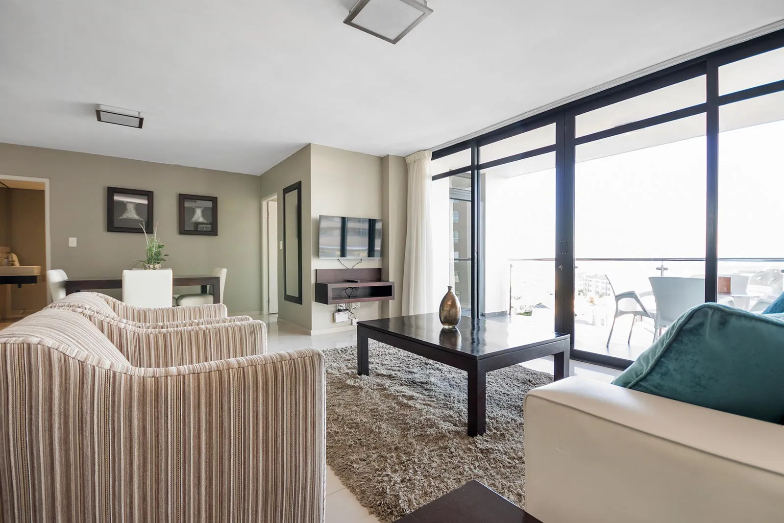 Modern living room with striped chairs coffee table and large windows to balcony