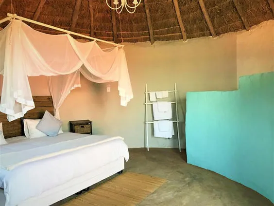Cozy bedroom with canopy bed towel rack and thatched ceiling