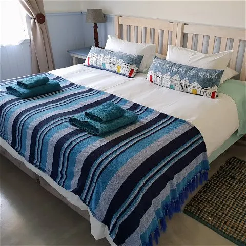 Cozy bedroom with neatly made bed blue striped blanket and decorative pillows