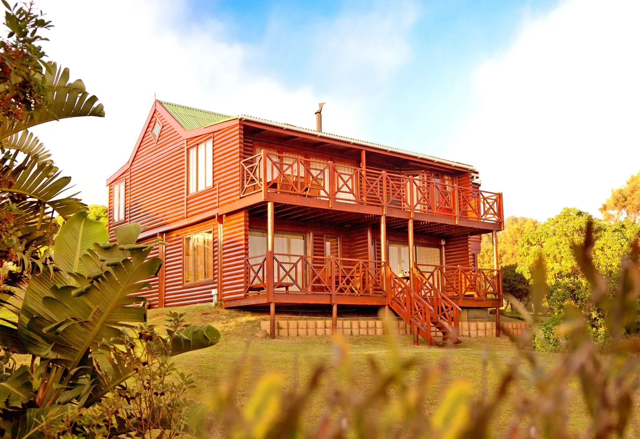 Wooden house with balconies in a lush garden under a clear sky