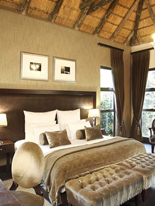 Cozy bedroom with large bed, pillows, and a bench in front.