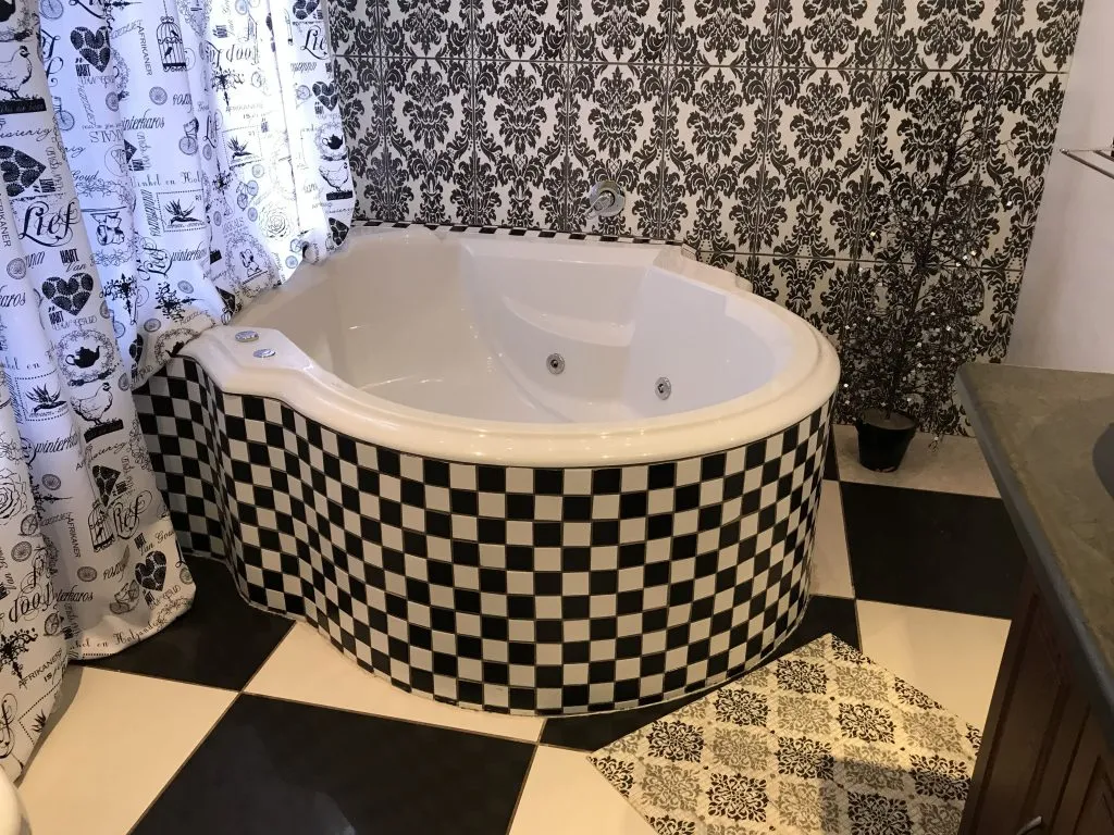 Black and white checkered hot tub in a patterned bathroom with a curtain