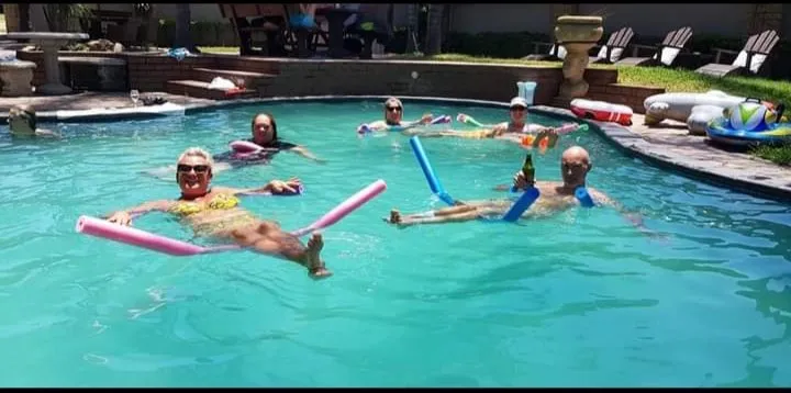 People relaxing in a swimming pool with inflatable pool noodles