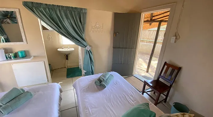 Two beds in a small room with a sink area and a door to outside