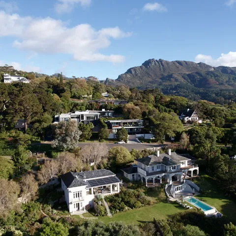Houses on a hillside with mountains in the background and a swimming pool