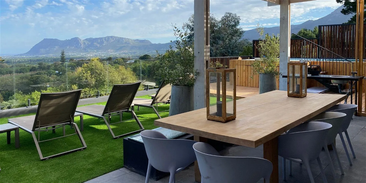 Outdoor patio with table chairs loungers and mountain view in the background