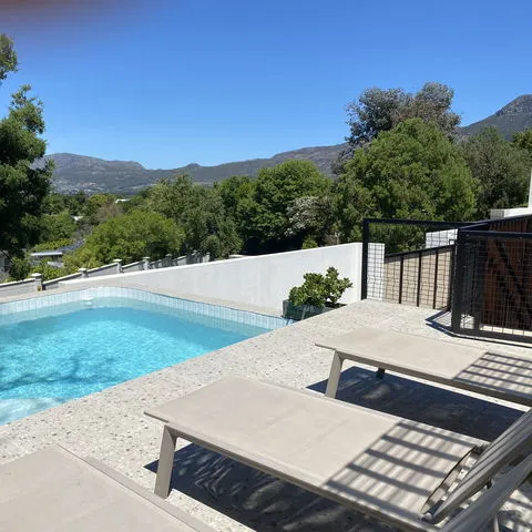 Swimming pool with lounge chairs trees and mountains in the background