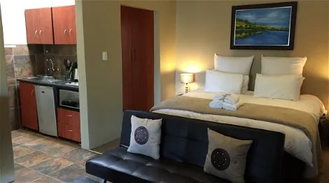 Cozy studio apartment with bed kitchenette and artwork above the bed