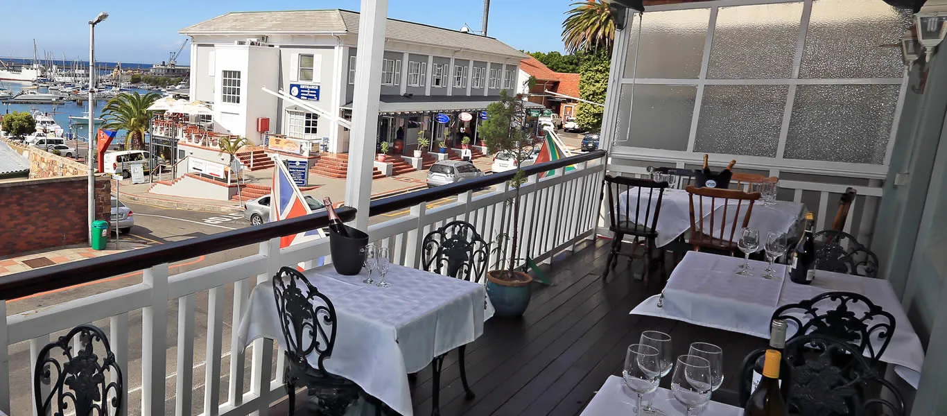 Outdoor dining area with tables set for a meal overlooking a harbor