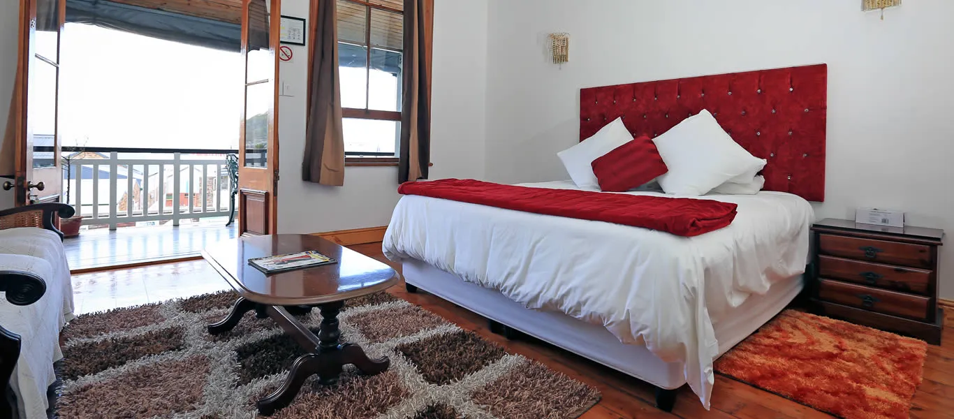Cozy bedroom with large bed red accents and a view of a balcony