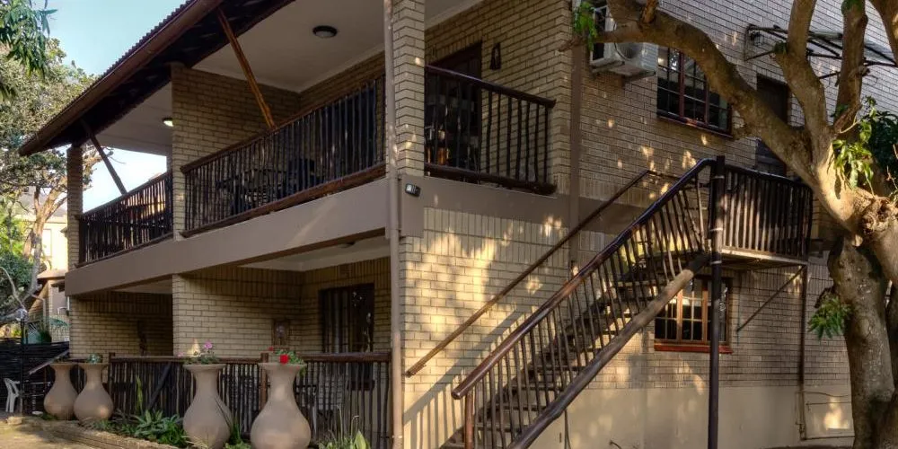 Twostory building with balconies exterior staircase and large vases in front