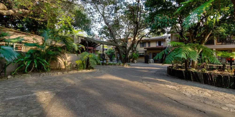 Pathway surrounded by trees and plants leading to a building with balconies