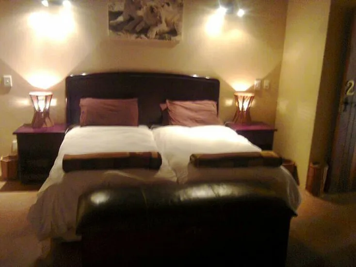 A neatly made bed in a dimly lit bedroom with bedside lamps