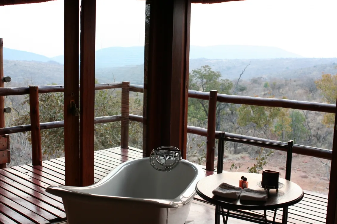Bathtub on a wooden deck with a scenic mountain view through open doors