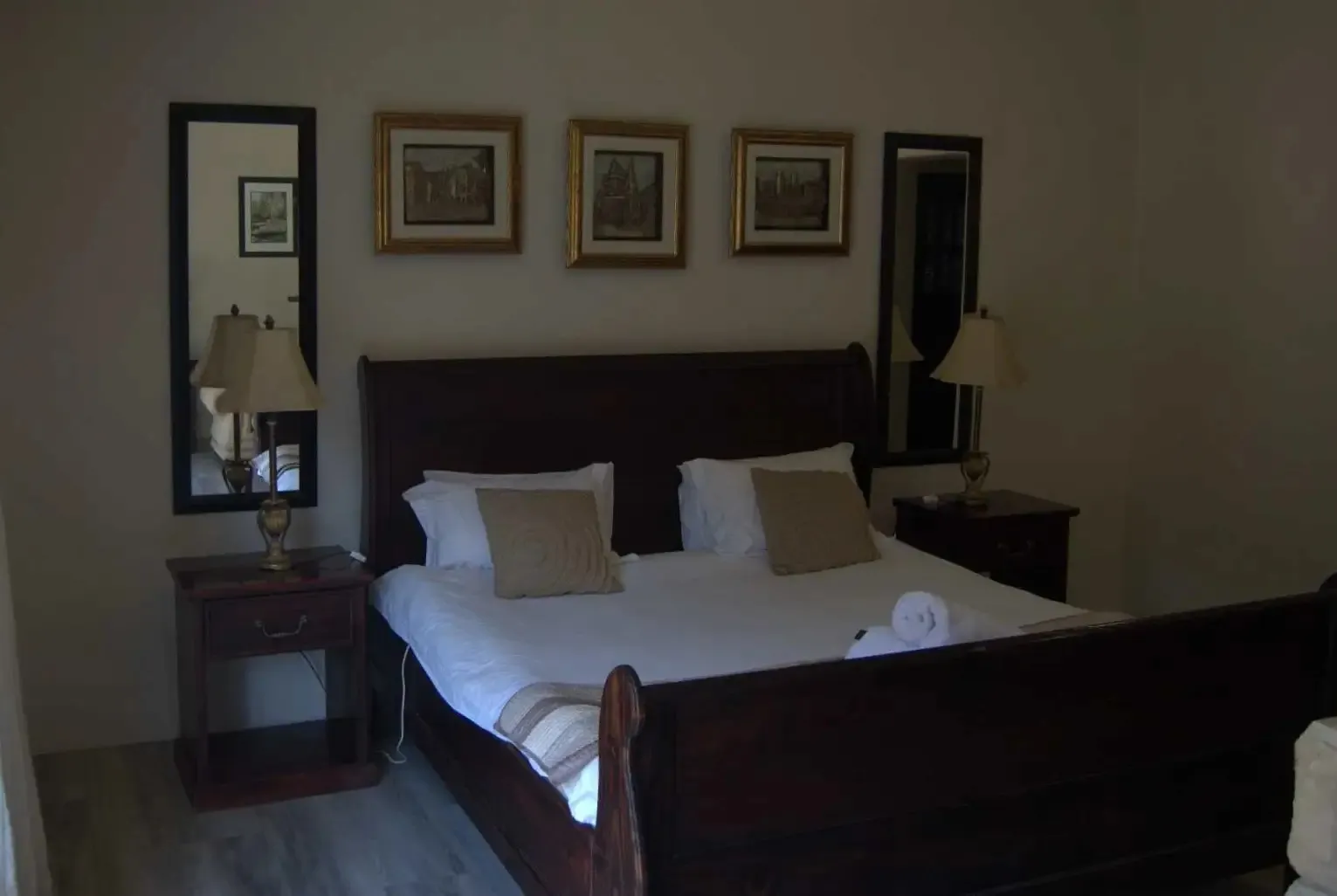 A large bed with wooden frame pillows and bedside tables with lamps