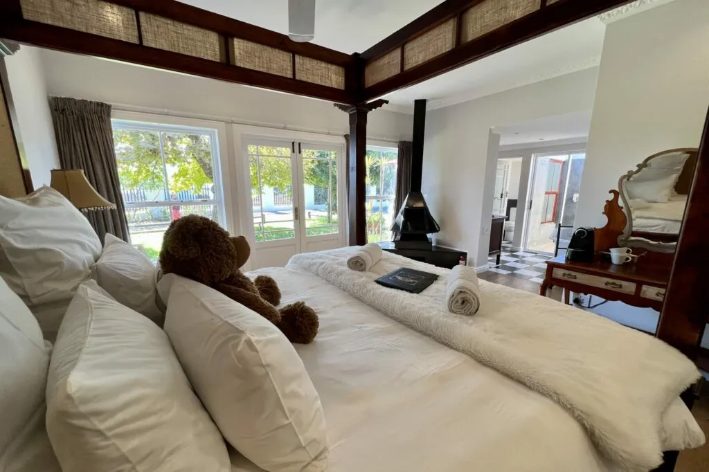 Cozy bedroom with teddy bear on bed large windows and fireplace