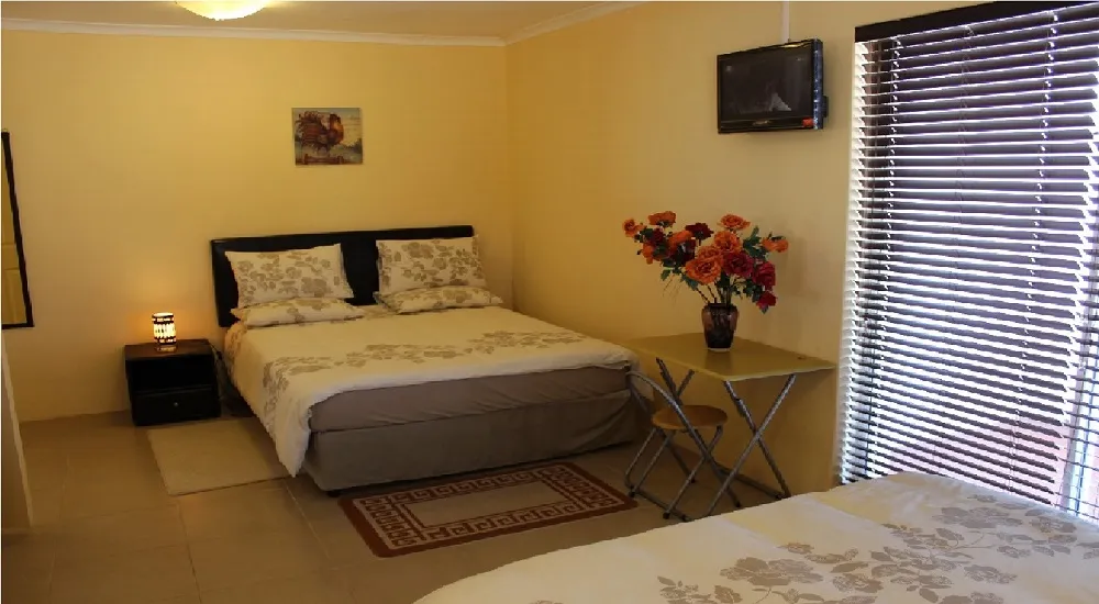 Bedroom with two beds side table TV and window blinds