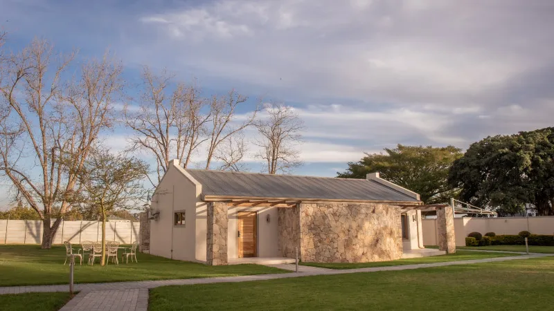 Small stone cottage with a grey roof in a grassy area with trees