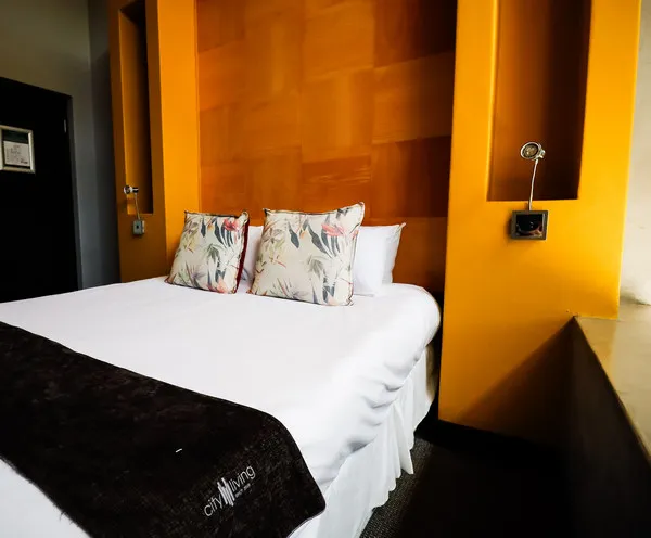Modern bedroom with orange walls floral pillows and a black throw blanket