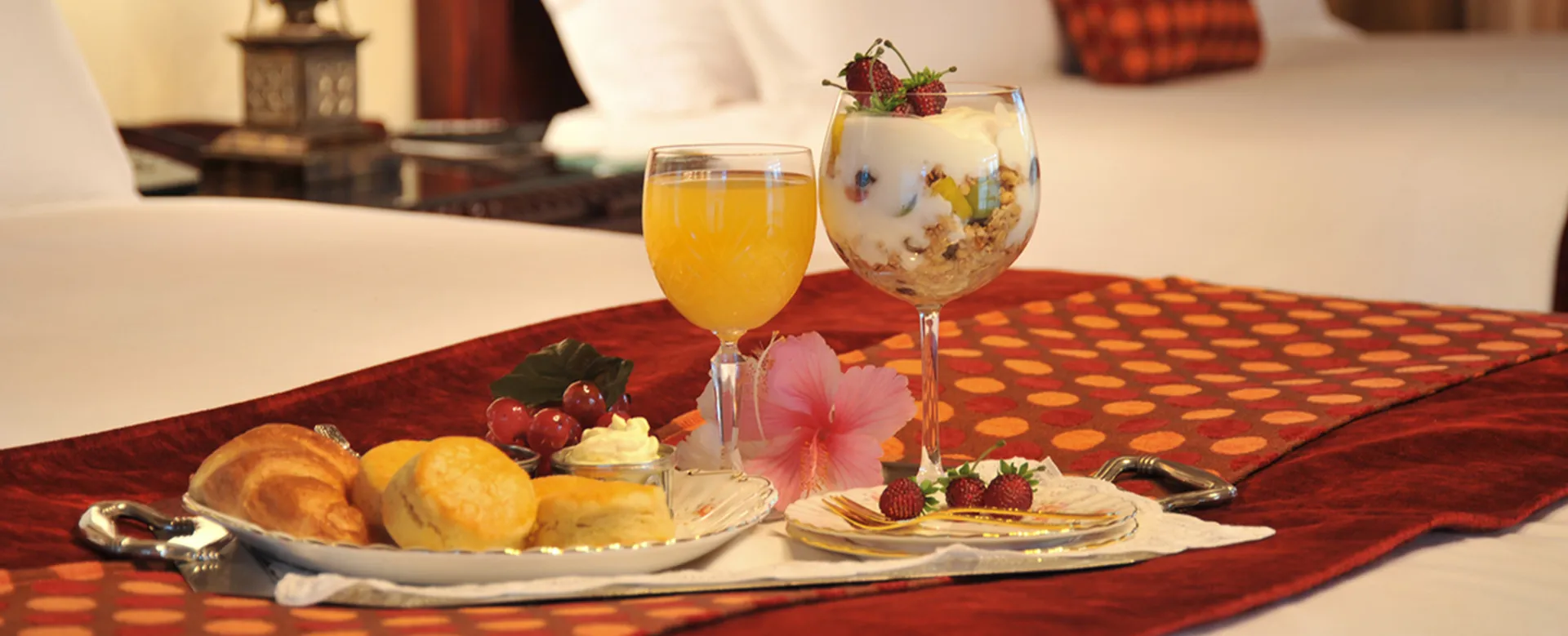 Breakfast tray with pastries juice and parfait on a bed