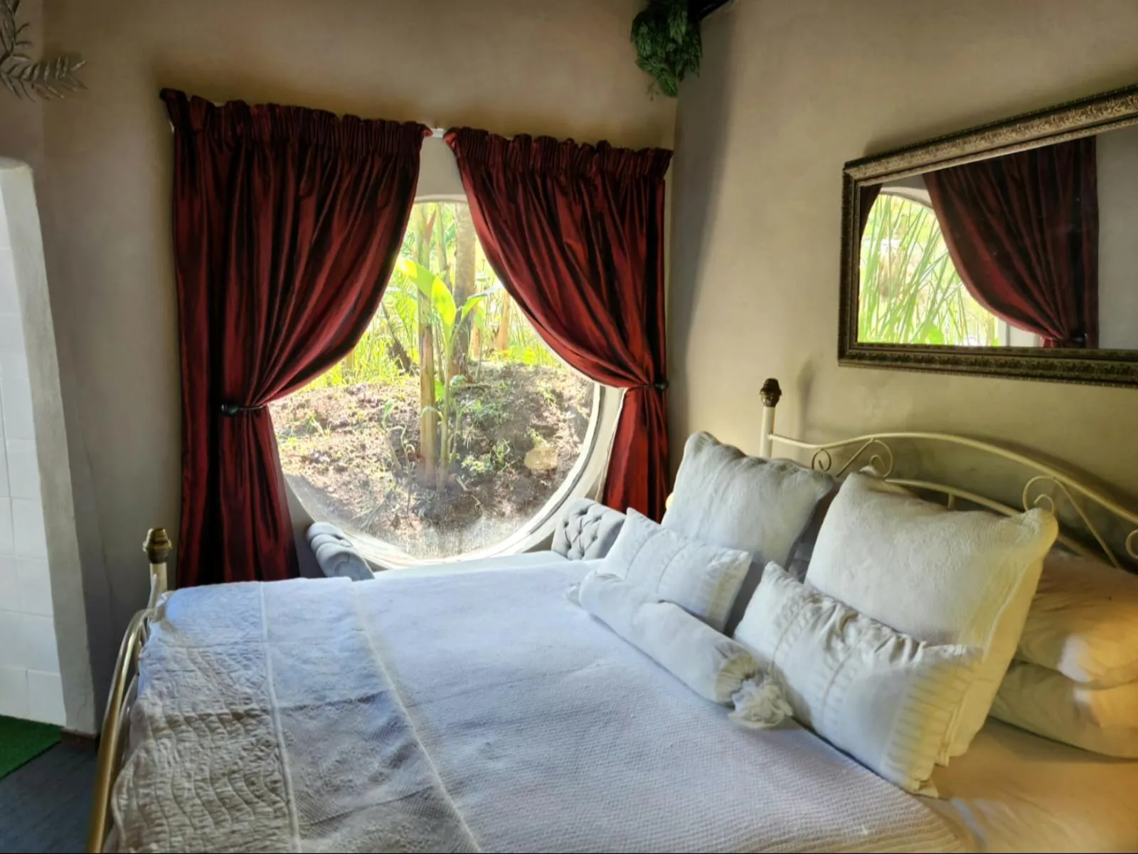 Cozy bedroom with large round window red curtains and white bedding