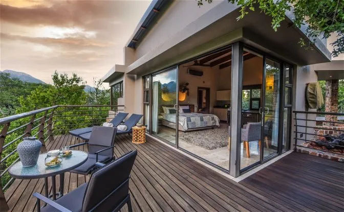 Modern wooden deck with furniture overlooking a bedroom with large windows and scenic view