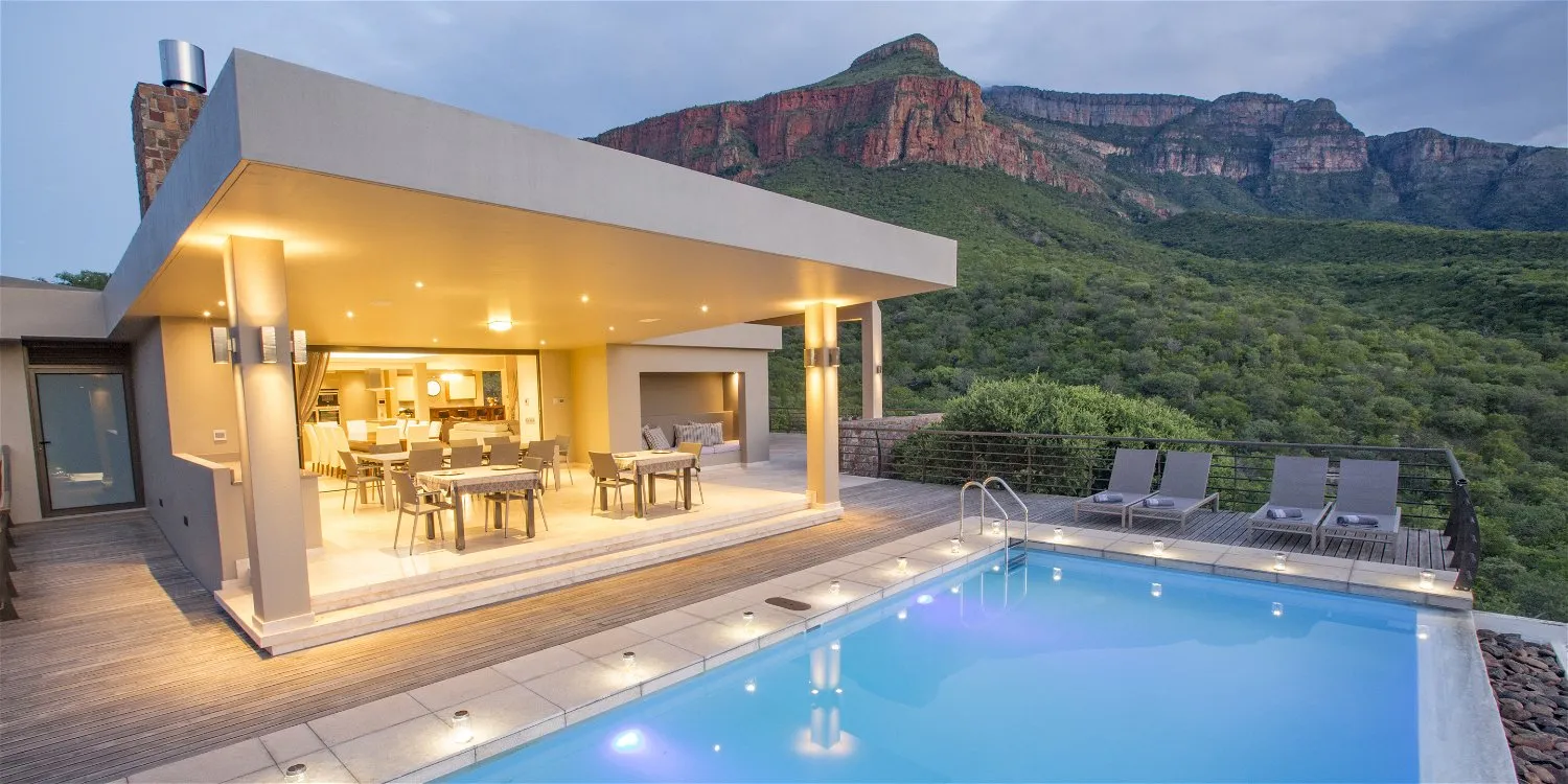 Modern house with pool lounge area and mountain view at dusk